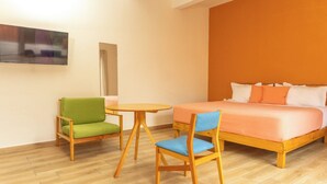 A hotel room with a bed, two chairs, a small table, and a TV mounted on the wall. - REGIONES - CAÑADA · Charming Upper Floor Suite (Oaxaca de Juárez)