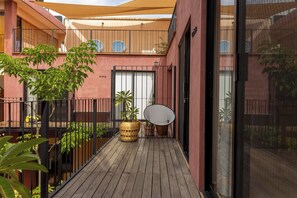A wooden deck with potted plants, a wicker basket, and a metal chair.