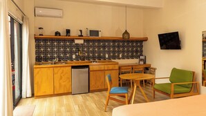 A compact kitchen with a microwave, toaster, and coffee maker, a dining area with a table and chairs, and a TV mounted on the wall. - REGIONES - CAÑADA · Charming Upper Floor Suite (Oaxaca de Juárez)