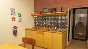 Cocina compacta con encimera de madera, microondas, fregadero y extintor.