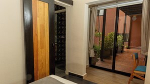Una habitación con una cama, un ventanal corredizo que da a un área exterior con una silla y una planta en maceta.