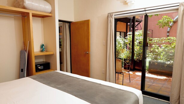Un dormitorio con cama, repisa de madera, armario y puerta corredera de vidrio que da a un patio exterior.
