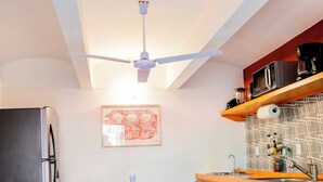 Une cuisine moderne avec une table à manger en bois, un ventilateur de plafond et un four à micro-ondes.