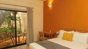 Ein Hotelzimmer mit Bett, kleinem Tisch, Stuhl und Blick nach draußen.