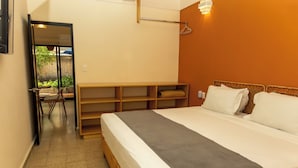 Ein Hotelzimmer mit einem Bett, einer Holzbank, einem Spiegel und einer Wandleuchte.