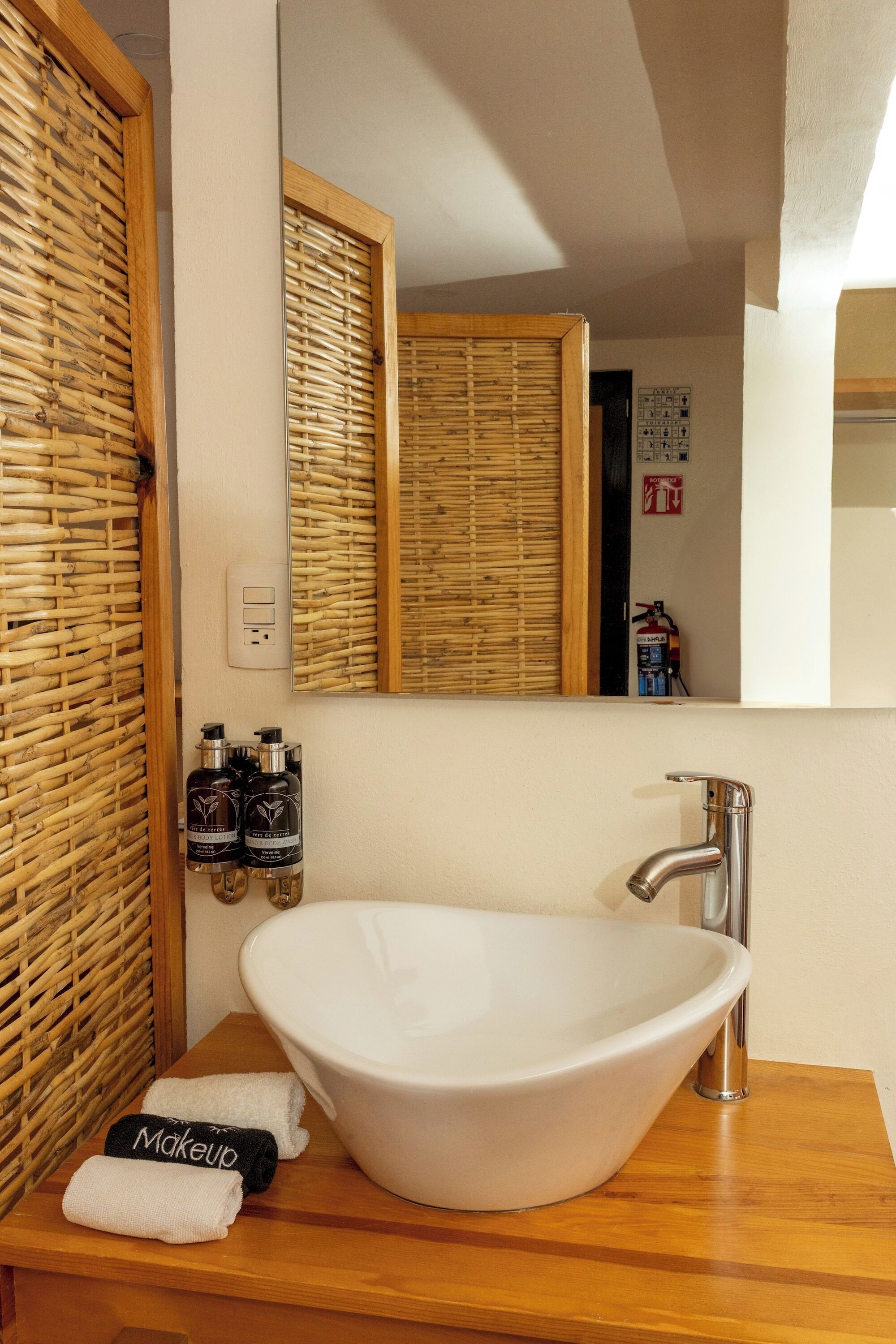 A bathroom with a white sink, wooden vanity, and a mirror.
