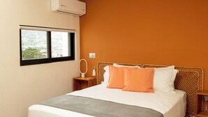 Une chambre d’hôtel équipée d’un lit, d’un appareil de climatisation, d’une fenêtre et d’une table de chevet avec un miroir.