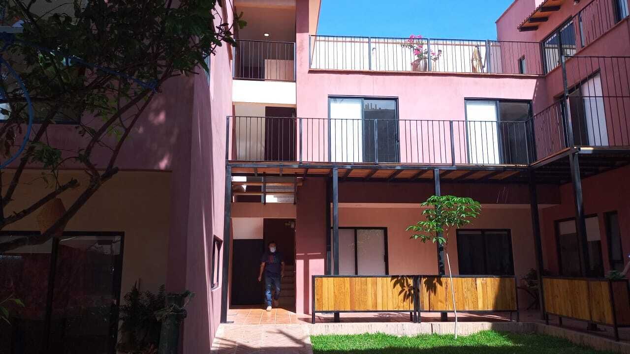 Un edifici de diverses plantes amb balcons, un pati central i una persona caminant.