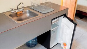 Eine Küche mit Spüle, Geschirrgestell, Kühlschrank und blauem Wasserspender.