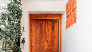 Eine Holztür mit Klingel, eine zur Tür hinaufführende Treppe und eine Wandleuchte.