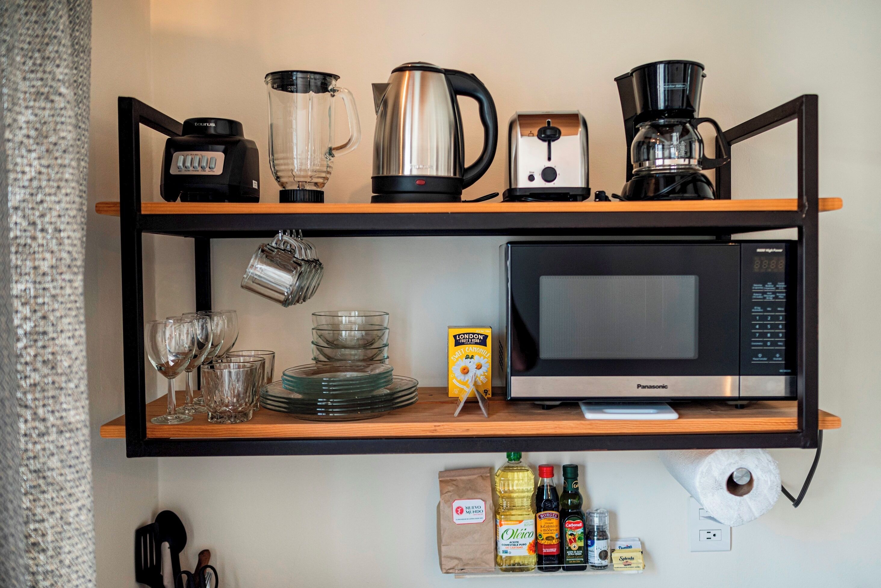 Une étagère de cuisine avec une machine à café, une bouilloire, un grille-pain et un four à micro-ondes.