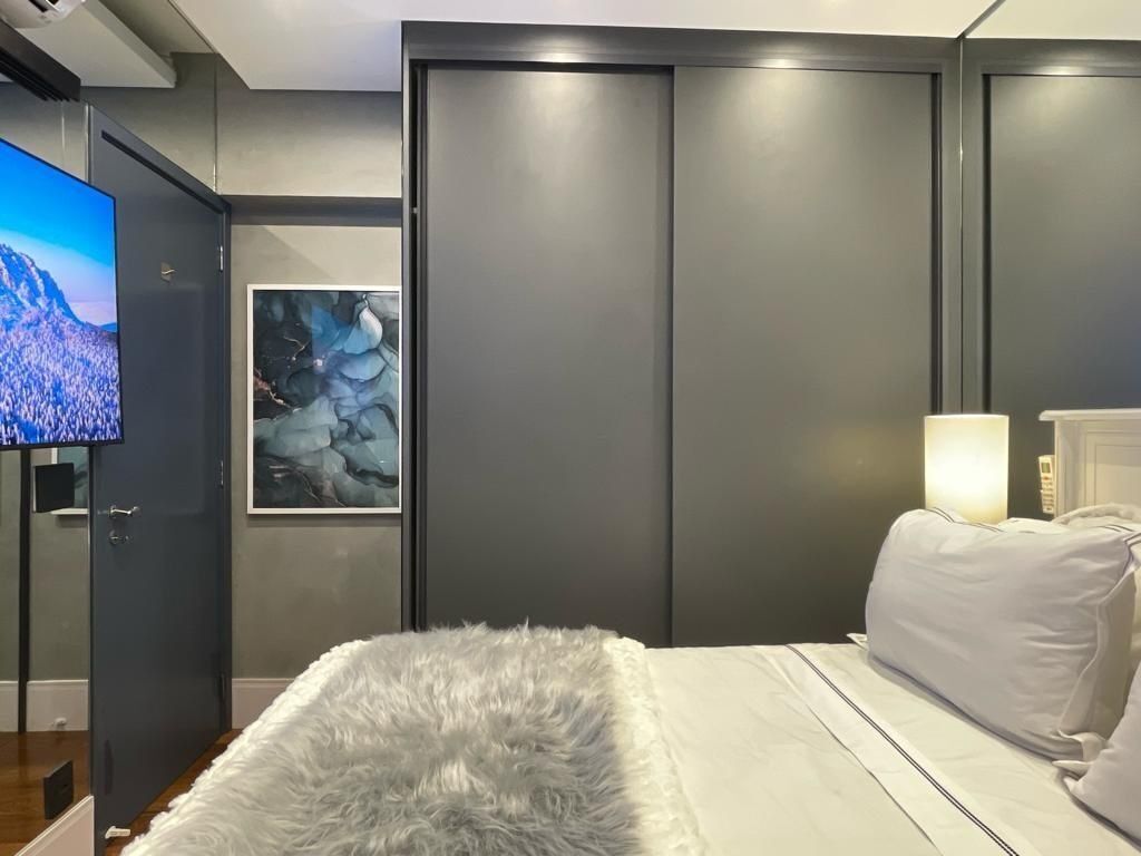 Un dormitorio con cama, televisor, un cuadro y armario.