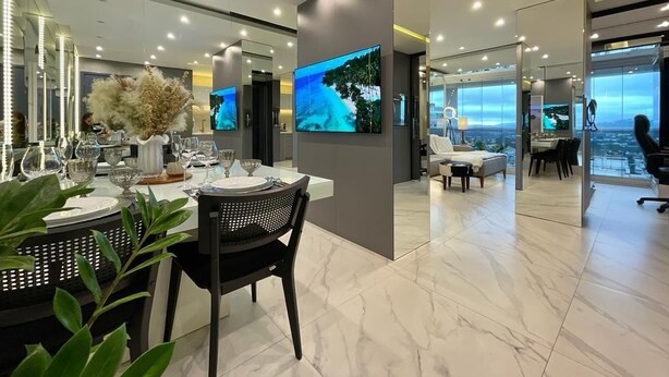 A modern dining area with a large TV screen, a dining table set with plates and glasses, and a view of the city through large windows. - Paris Luxury Apartment (Barueri)