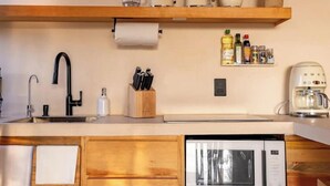 Une cuisine dotée de meubles en bois, d’un lave-vaisselle encastré, d’une machine à café et d’une étagère contenant des ustensiles de cuisine.