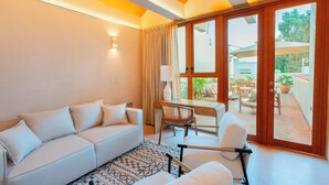 A modern living room with a sofa, a desk, and a chair. There is a large sliding glass door leading to an outdoor area with tables and chairs. - COLÓN · Luxury house with pool and terrace for 6 (Oaxaca)
