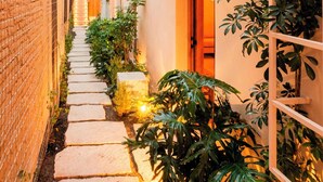A narrow pathway flanked by brick walls and white buildings, leading to a wooden door. - COLÓN · Luxury house with pool and terrace for 6 (Oaxaca)