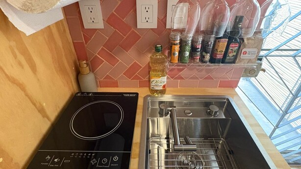 A kitchen with a built-in induction cooktop, a stainless steel sink, and a hanging wine rack. - GARCIA 5 · Tiny Room in the heart of Oaxaca (Oaxaca)