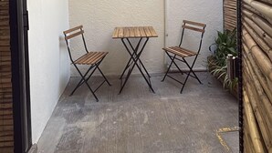 A small patio area with a table and two chairs, a bamboo fence, and a concrete floor. - GARCIA 5 · Tiny Room in the heart of Oaxaca (Oaxaca)