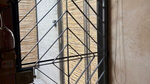 A metal gate with a geometric pattern, a concrete wall, and a glimpse of a building outside. - GARCIA 5 · Tiny Room in the heart of Oaxaca (Oaxaca)