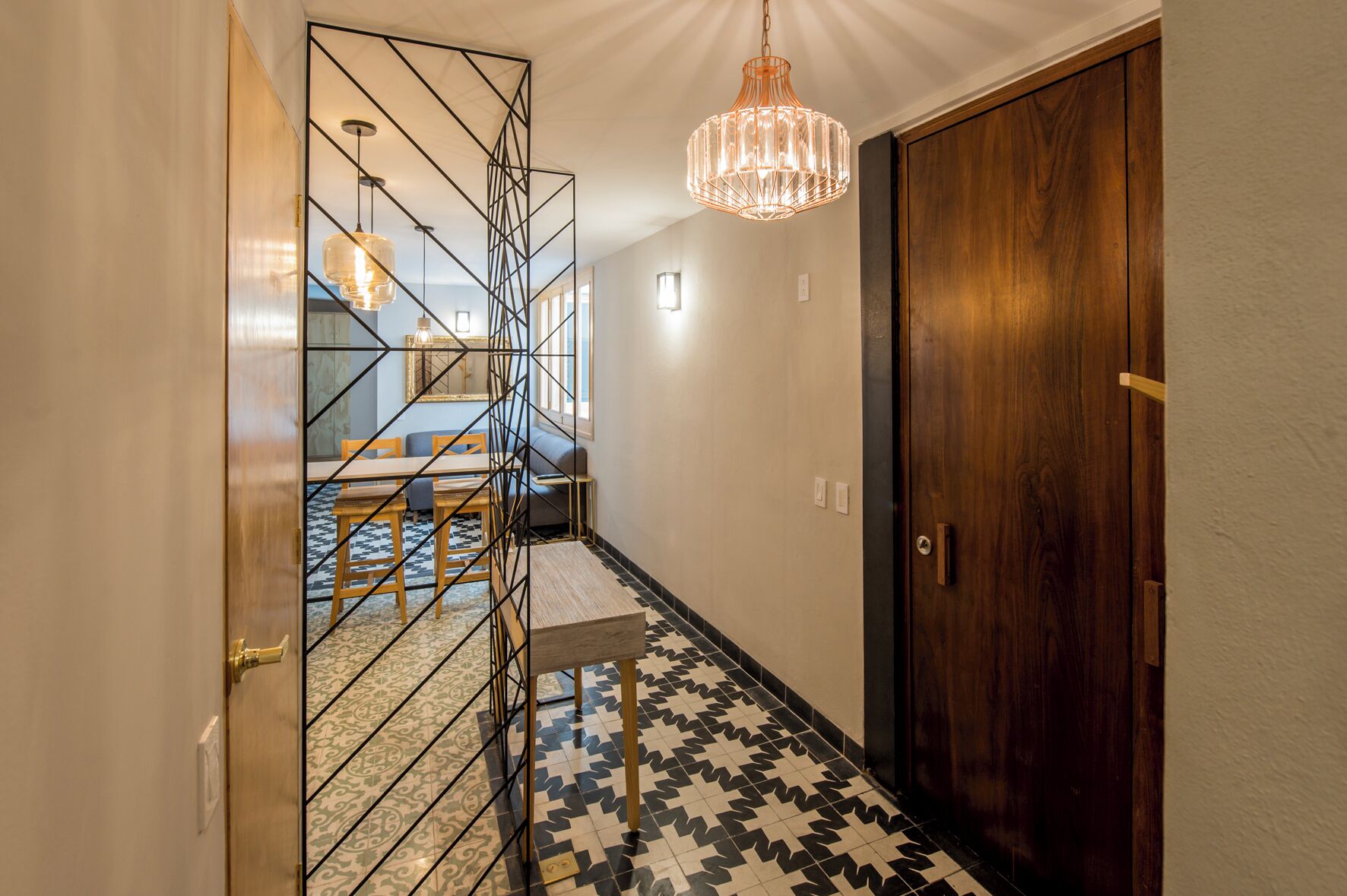 A hallway with a geometric metal partition, a wooden door, and a patterned floor.