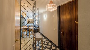 A hallway with a geometric metal partition, a wooden door, and a patterned floor.