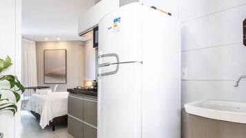 A modern kitchen with a white refrigerator, a sink, and a dining area with a table and chairs.