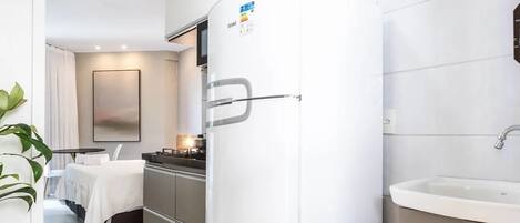 A modern kitchen with a white refrigerator, a sink, and a dining area with a table and chairs.