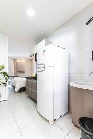 Una cocina moderna con un refrigerador blanco, un lavamanos y una zona de comedor con una mesa y sillas.