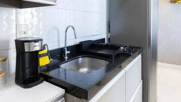 Una cocina moderna con electrodomésticos de acero inoxidable, encimera negra y un lavabo integrado.