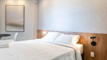 A modern hotel room with a large bed, a bedside table, and a wall-mounted light fixture.