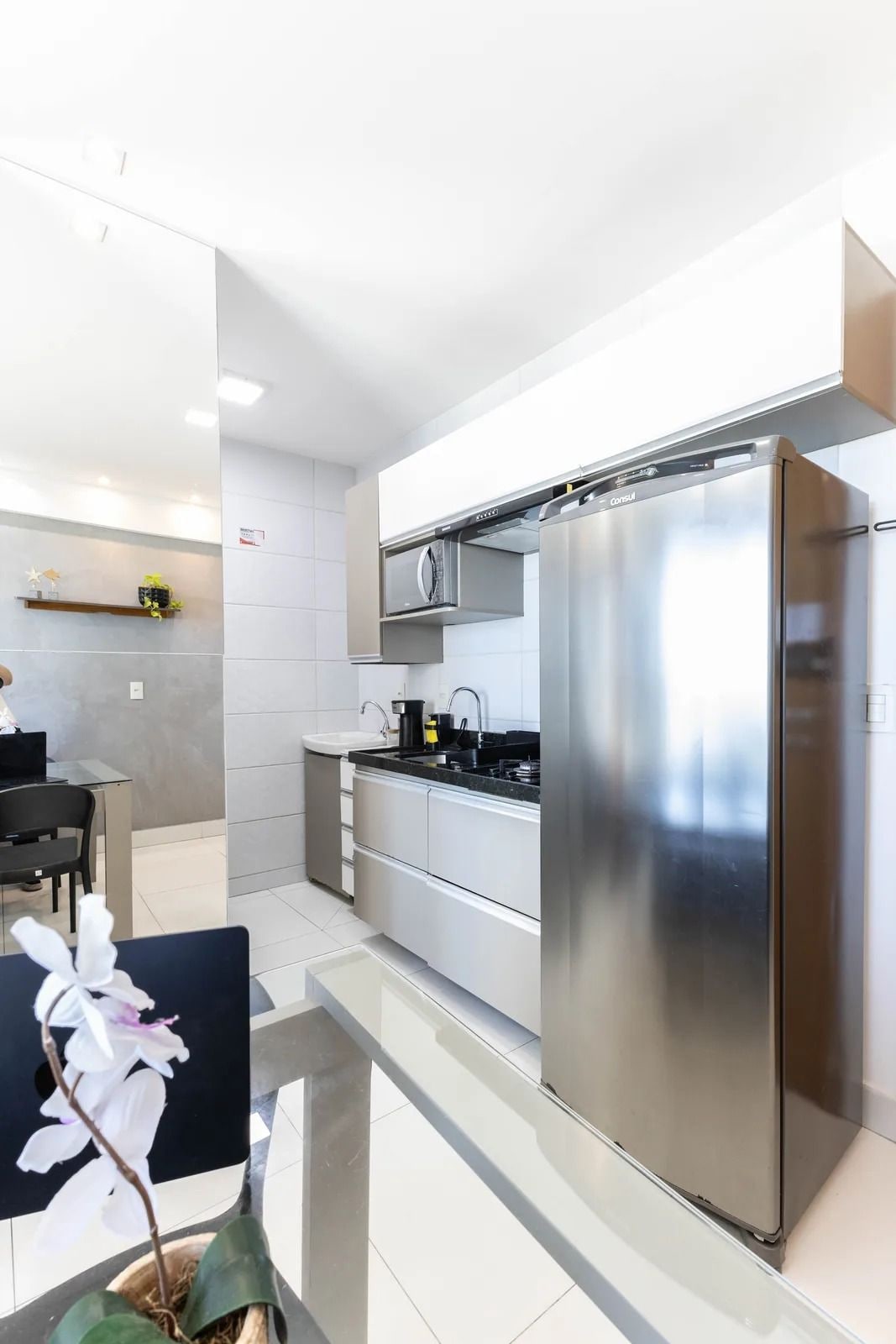 A modern kitchen with stainless steel appliances, a black countertop, and a dining area with a table and chairs.