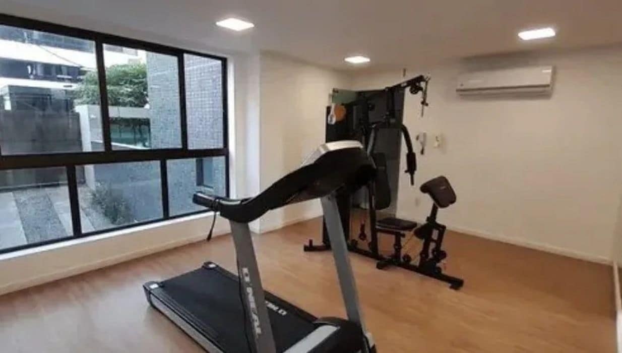 A gym with a treadmill, weight bench, and exercise equipment.