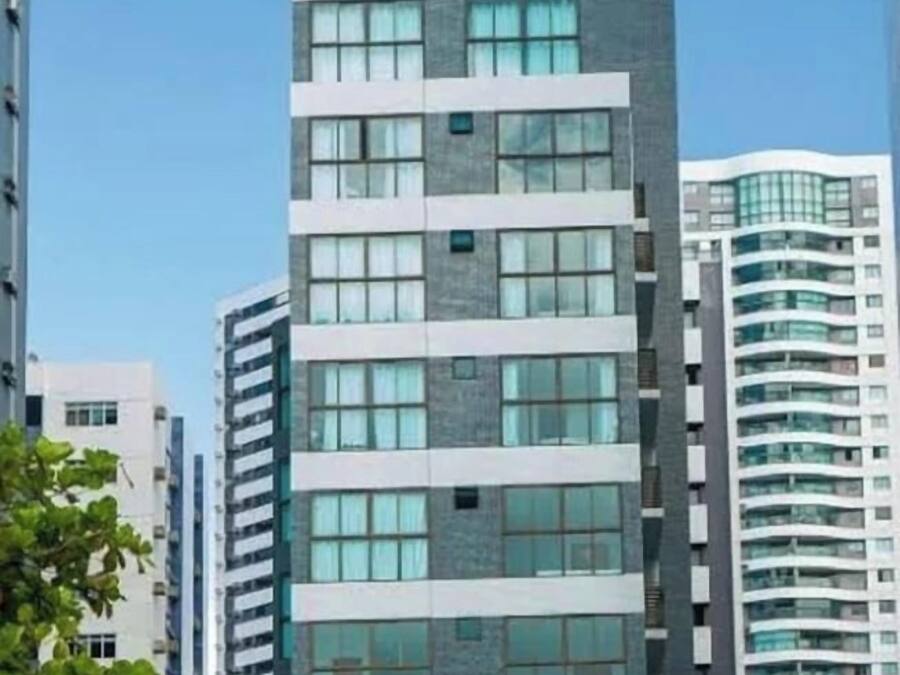 Un edificio de varios pisos con un diseño arquitectónico moderno, que combina fachada de vidrio y piedra y una serie de balcones.