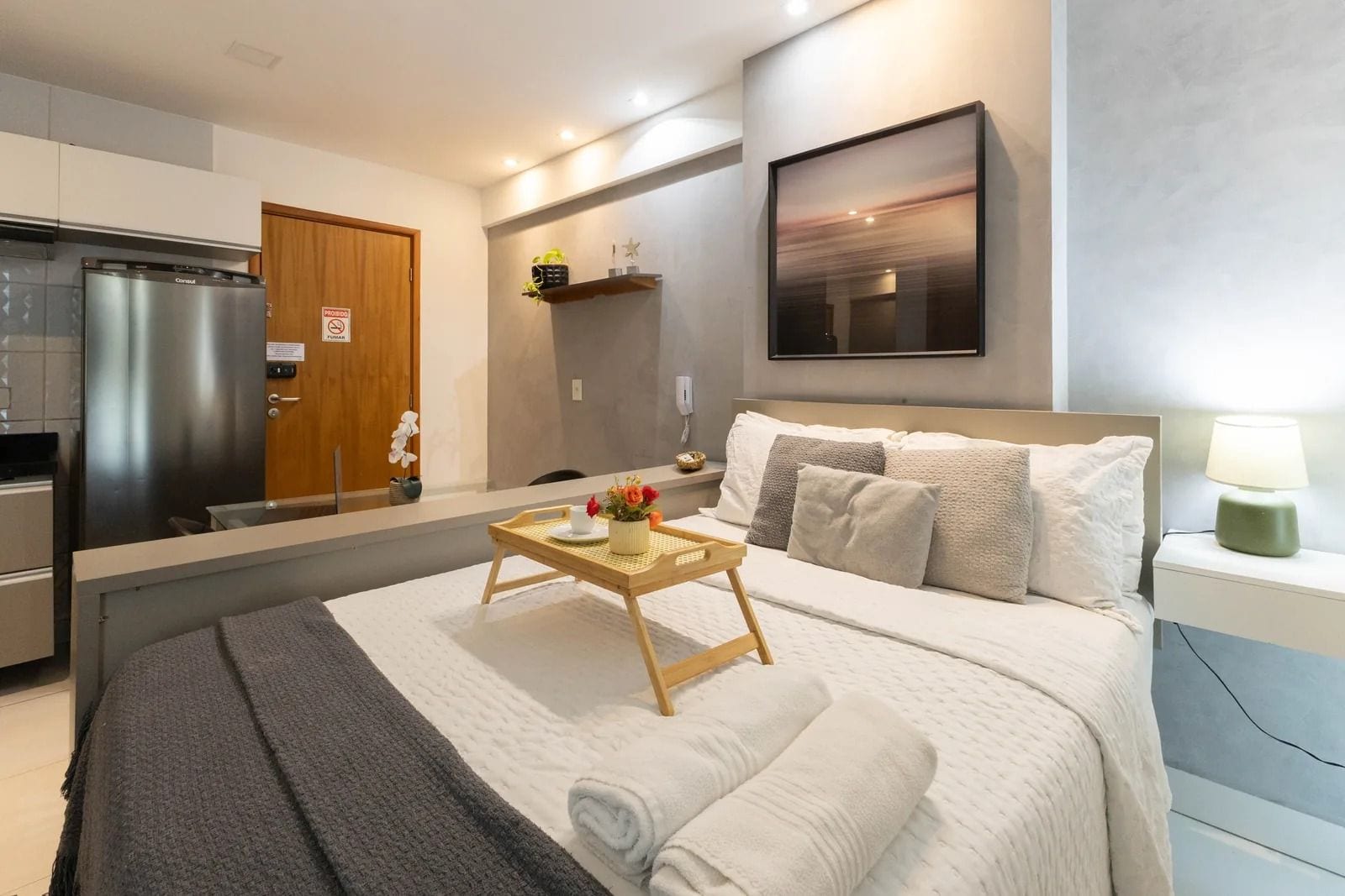 Una camera d'albergo moderna con un letto, un comodino e vista sulla cucina.