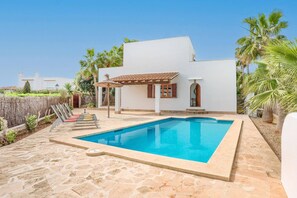 Ett modernt hus med en swimmingpool, en pergola och utsikt över det omgivande landskapet.