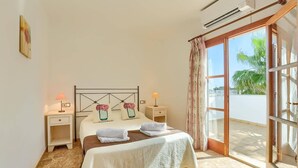 Een slaapkamer met een bed, twee nachtkastjes, een raam met gordijnen en een airconditioning.