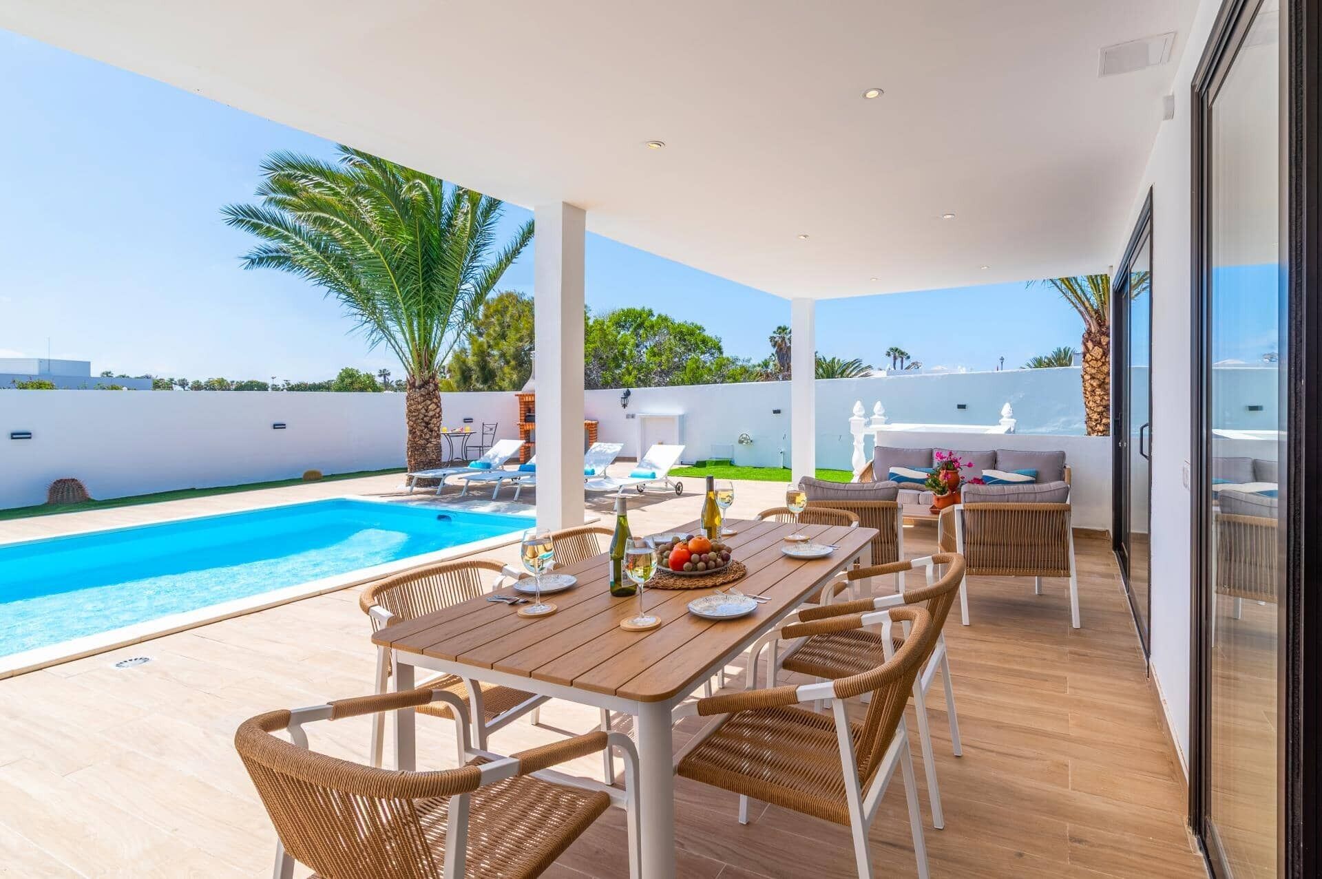 A poolside area with a table set for dining, lounge chairs, and a view of the pool.