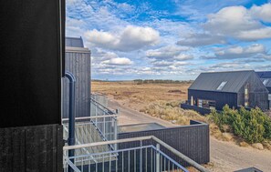 Een modern gebouw met een metalen wenteltrap en uitzicht op een landelijk gebied.