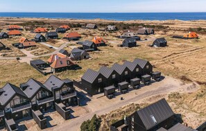 Een kustdorp met meerdere huizen, waarvan er enkele rode daken hebben, en een opvallend gebouw met een balkon.
