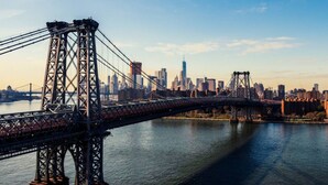 A large suspension bridge spanning a river with a city skyline in the background. - Simple, Quiet & Clean w/ Workstations (New York)
