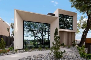A modern building with large windows, a concrete pathway, and a small garden area.