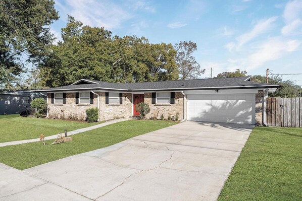 Une maison de plain-pied avec un garage, une pelouse devant et une clôture en bois.