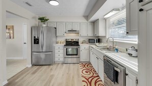 Een moderne keuken met witte kasten, roestvrijstalen apparatuur, een inbouwoven, magnetron en een spoelbak.
