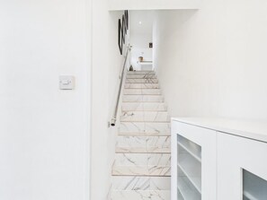 Een trap met witte marmeren treden die naar een kamer leidt met een witte kast.