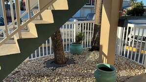 A balcony with a railing, potted plants, and a gravel ground. - Tranquil 1-bedroom condo with AC in Madeira Beach completely updated . (Madeira Beach)