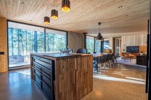 A modern kitchen with wooden cabinetry, a central island, and pendant lighting. - Spa and Escape by the Water | Loveshack (Saint-Alphonse-Rodriguez)