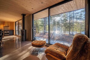 A modern interior with a large window, a sofa, and a kitchen area. - Spa and Escape by the Water | Loveshack (Saint-Alphonse-Rodriguez)