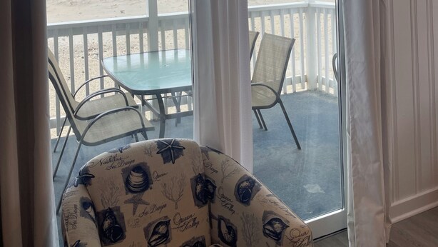 A room with a glass door leading to a balcony with a view of the beach. - Cozy 2-bedroom condo located directly on Hampton Beach with AC (Hampton)
