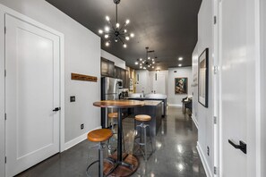 Eine moderne Küche mit Edelstahlgeräten, einer Bar mit Barhocker und einer Deckenleuchte.