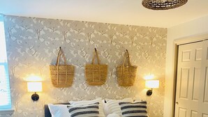 Une chambre à coucher avec un lit, des lampes de chevet, un panier fixé au mur et une porte.